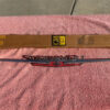 Close-up of 1962 Chevrolet Chevy II Nova hood lip emblem part number 3792812 original NOS chrome trim piece