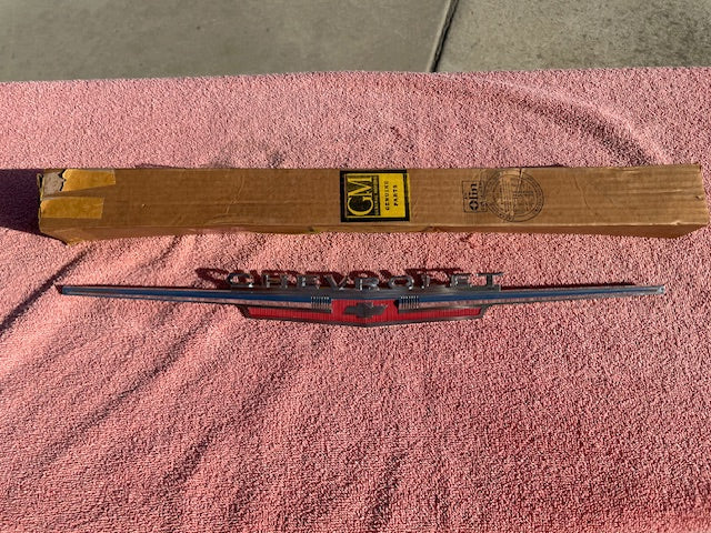 Close-up of 1962 Chevrolet Chevy II Nova hood lip emblem part number 3792812 original NOS chrome trim piece